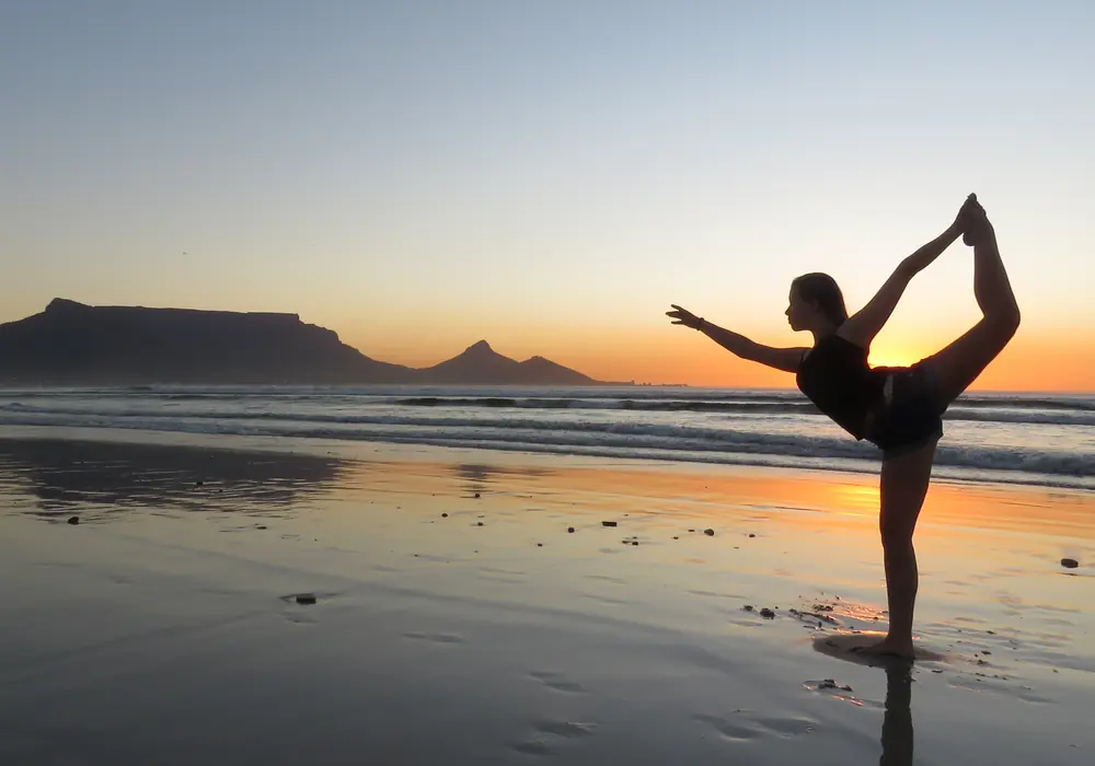 Silhouette in dancer pose on a wet beach at sunset