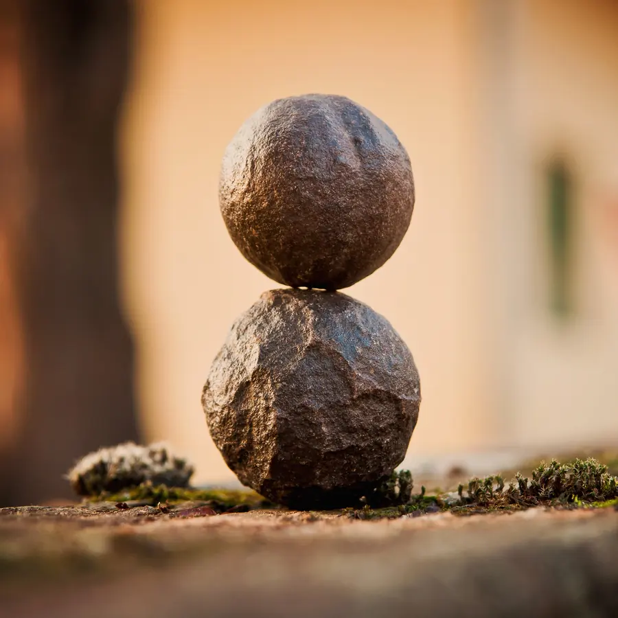 Two smooth stones balanced on a mossy ledge in warm evening light